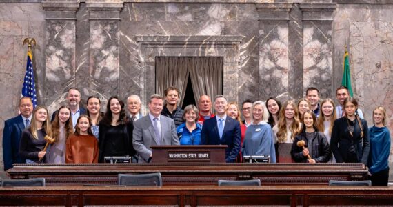 Sen. Mark Mullet, Sen. Brad Hawkins, Representative Lisa Callan, the Mt. Si Girls Cross Country Team and their families pose for a group photo in the Senate chambers, alongside staff from the Snoqualmie Valley School District, Mayor Mary Miller of North Bend, and officials from the WIAA.