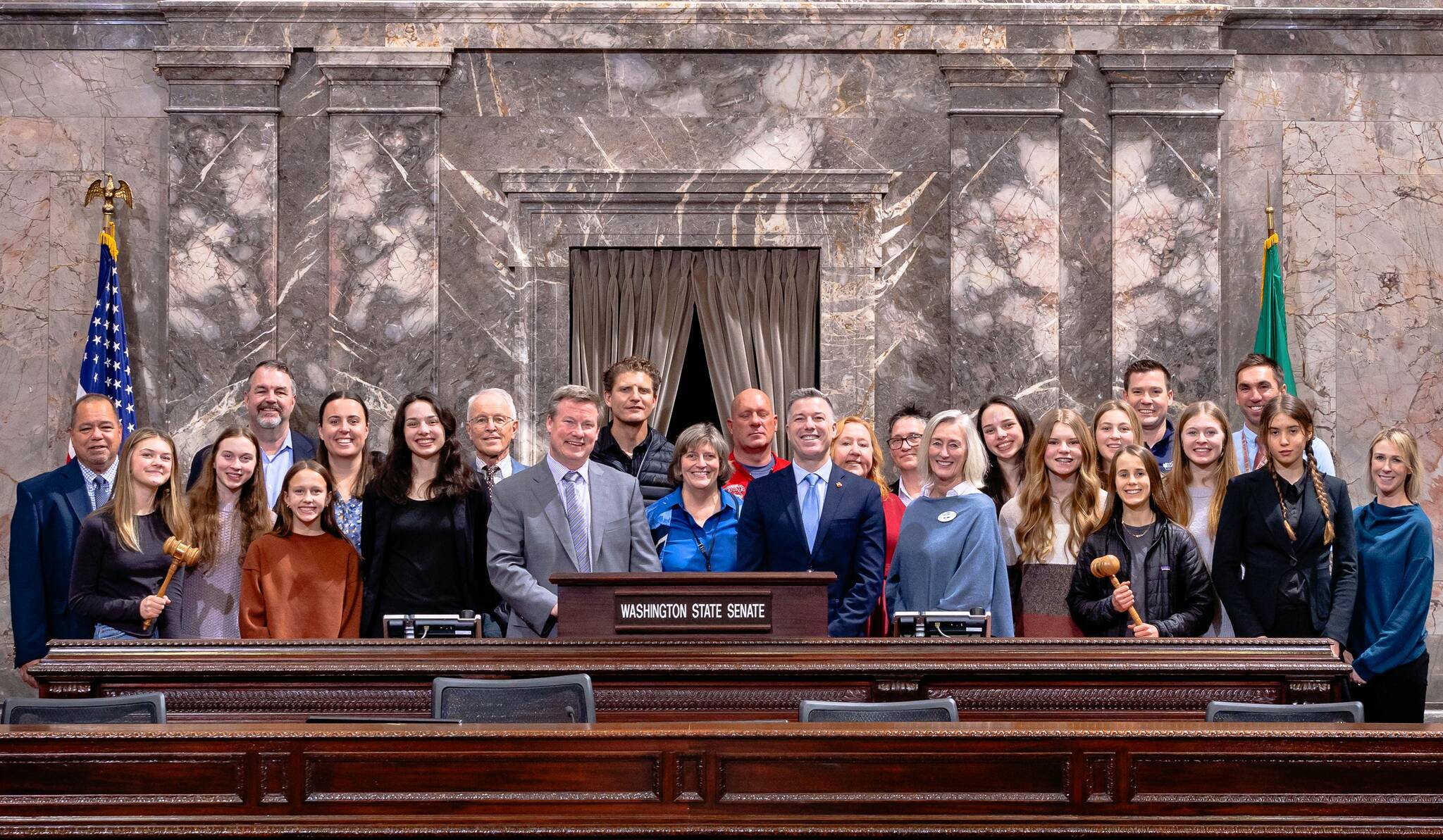 Sen. Mark Mullet, Sen. Brad Hawkins, Representative Lisa Callan, the Mt. Si Girls Cross Country Team and their families pose for a group photo in the Senate chambers, alongside staff from the Snoqualmie Valley School District, Mayor Mary Miller of North Bend, and officials from the WIAA.
