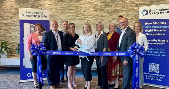 Snoqualmie Valley Health CEO Renée Jensen and radiologist Kara Carlson prepare to cut the ribbon at the opening of the hospital’s mammography suite, July 22, 2025. From left: Chief Nursing Executive Tricia Ralston; imaging department manager Steve Bradshaw; CFO Patrick Ritter; Jensen; Carlson; North Bend Mayor Mary Miller; board member Jen Carter; Chief Medical Officer Jeremy Storm; Snoqualmie Councilmember Rob Wotton; chief of strategic operations Tammy Moore. (Grace Gorenflo/Valley Record)