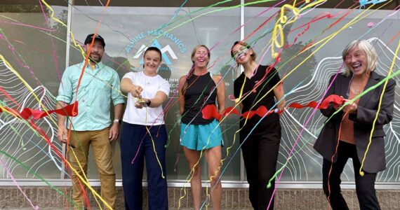Theresa Haley cuts the ribbon at a ceremony for her physical therapy clinic, Alpine Mechanics, in North Bend, July 31, 2025. She is joined by her husband, her staff and North Bend Mayor Mary Miller (right). Grace Gorenflo/Valley Record