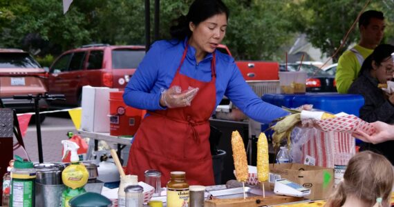 A vendor serves corn to a customer at the North Bend Farmers Market, Sept. 11, 2025. (Grace Gorenflo/Valley Record)