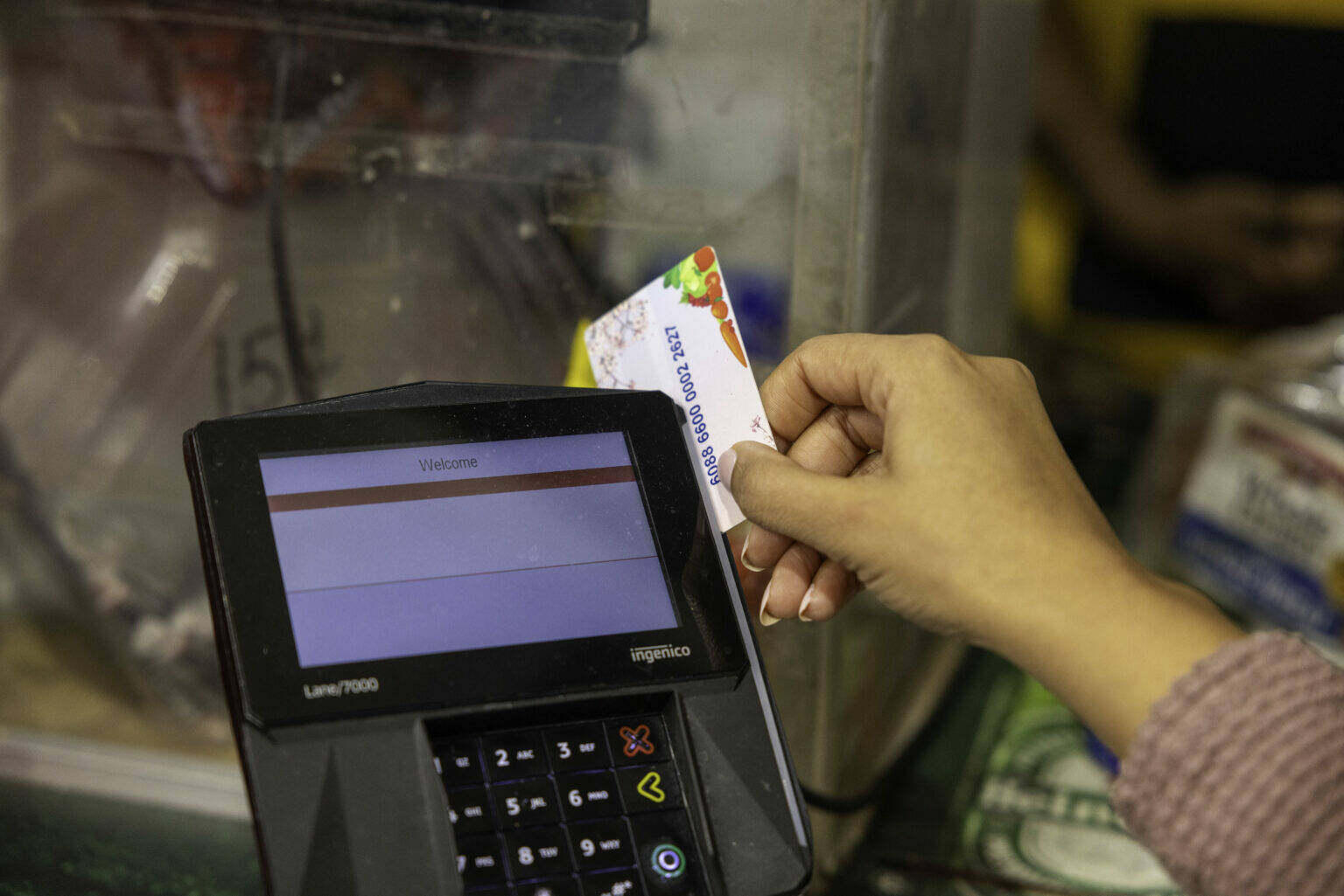 A shopper who receives SNAP benefits slides an EBT card at a checkout counter in a Washington, D.C., grocery store in December 2024. ( U.S. Department of Agriculture)