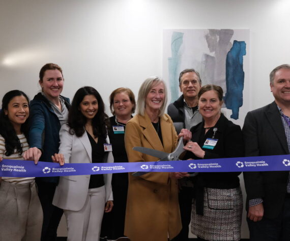 Snoqualmie Valley Health CEO Renee Jensen (right) and North Bend Mayor Mary Miller cut the ribbon on the new clinic, Nov. 19, 2025. They are surrounded by SVH providers and leaders. (Grace Gorenflo/Valley Record)