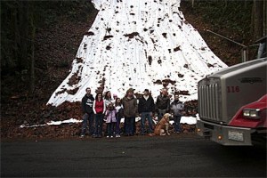 Middle Fork residents watch one of the many semi-trucks traveling on one-way Middle Fork Road. After a landslide closed a nearby artery