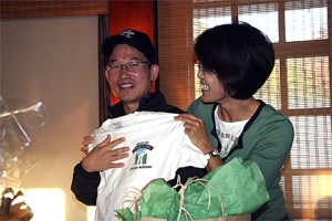 Young Hoon Mun gets help from wife Jae in modeling a souvenir shirt