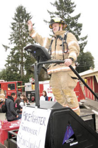 Fall City firefighter Brett Krache waves to passing cars outside Farmhouse Market Saturday afternoon
