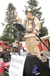Fall City firefighter Brett Krache waves to passing cars outside Farmhouse Market Saturday afternoon