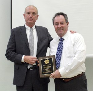 King County Sheriff John Urquhart presents a plaque of recognition Tuesday to North Bend councilman Ryan Kolodejchuk for his work in helping move the remains of fallen county police dogs.