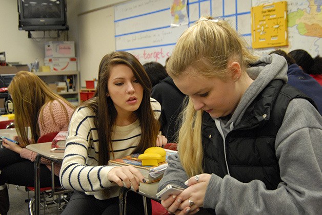 Mount Si High School student Maddi Brown shows Hunter Abbott-Heutmaker where to find information on a website on her phone.