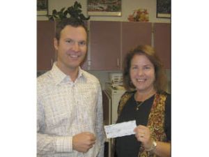 Fall City Days committee President Judy Dix presents Fall City Elementary School Principal Dan Schlotfeldt a check for $1
