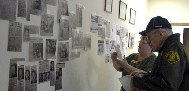 Retired King County Policeman and North Bend office Roger Connelly explores the wall of clippings with Office Manager Kym Smith