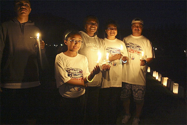 The Yoshitomi family lights candles as darkness falls and luminaria glow at last year's Snoqualmie Valley Relay for Life. Hundreds walk