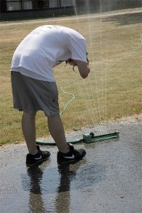 A teen at Echo Glen Children’s Center in Snoqualmie beats the heat with a soak in a sprinkler during the Relay for Life. The event helps insill a sense of caring.