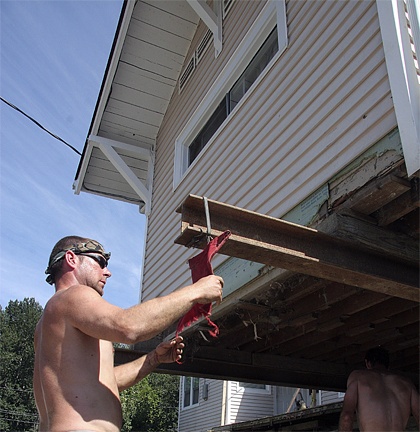 Bob Cook hangs a red flag on the steel I-beam supporting a downtown Snoqualmie home in the process of being raised. Valley-based Emerald Pacific Development is raising two homes this fall and bidding for more under a federal flood-protection grant with help from the City of Snoqualmie.