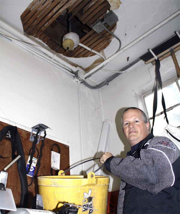 EFR firefighter Terry Cushman grabs the catchbasin for a roof leak at the North Bend fire station. Crew members deal with problems including leaks