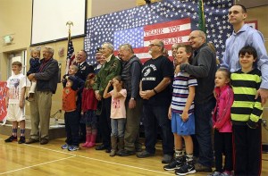 All the veterans and their children in attendance line up for a picture under the “Thank you Veterans” sign created by Cascade View students.