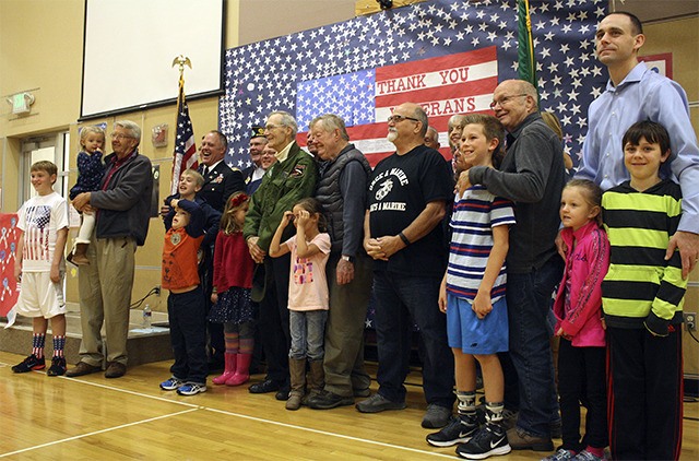 All the veterans and their children in attendance line up for a picture under the “Thank you Veterans” sign created by Cascade View students.