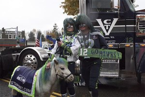 Mr. and Mrs. Seahawk pose for a photo with Wilson the 12th pony in front of a Wheels of Boom truck.