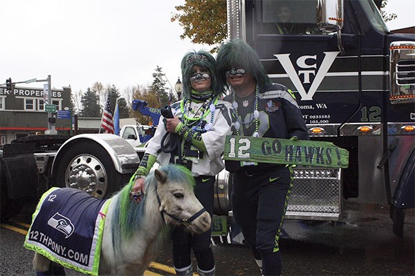 Mr. and Mrs. Seahawk pose for a photo with Wilson the 12th pony in front of a Wheels of Boom truck.