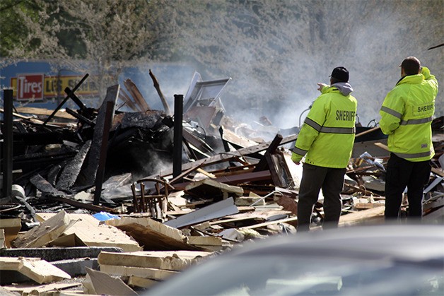 King County deputies go over the smoking ruins of the Pizza Place and neighboring businesses following the April 25 explosion in downtown North Bend.