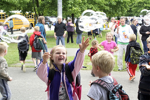 First grader Olivia O’Neill plays in the breeze of bubbles as Opstad Elementary School wraps up classes Wednesday