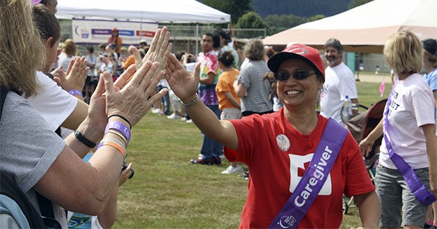 Cancer caregiver Angi Reyes gives a high-five to a row of cheering onlookers during the starting Survivor Lap of Snoqualmie Valley Relay for Life