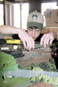 Northwest Railway Museum volunteer Isaac Farrar carefully settles a model train car onto its tracks on a new museum diorama. Volunteers including Farrar spent hundreds of hours creating the mock-up of the future campus