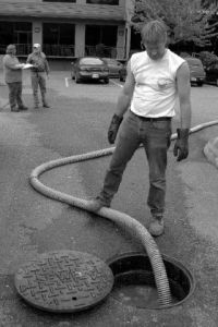 Bernell Stigen vacuums up raw sewage from an overflowing manhole in the parking lot of Preston Industrial Park