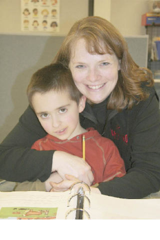 First-grader Trevor Moon sits on teacher Sally Combs’ lap as he works on a journal. Combs’ physical approach is one of the ways she adapts to her students’ autism