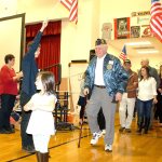 Evan Pappas/File Photo                                Bob Hamerly enters the Snoqualmie Elementary School gym, welcomed by flag-waving pupils at the 2015 Veterans Day assembly.