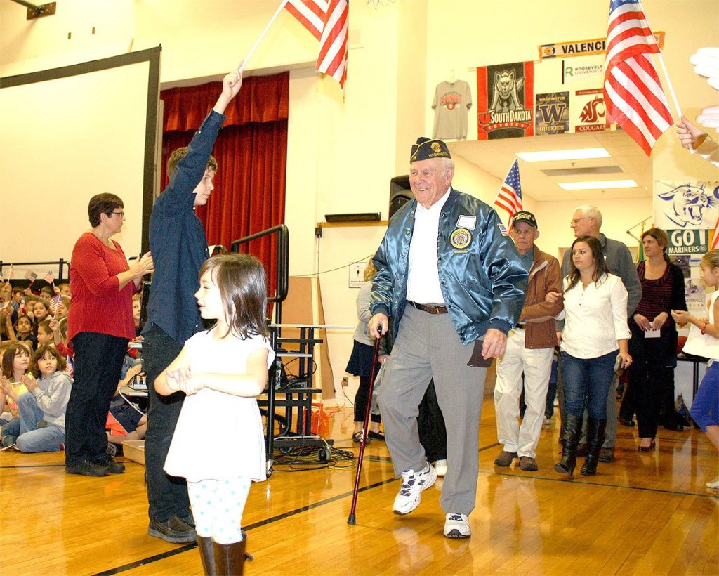 Evan Pappas/File Photo                                Bob Hamerly enters the Snoqualmie Elementary School gym, welcomed by flag-waving pupils at the 2015 Veterans Day assembly.