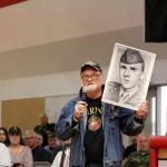 Artist and founder of the Fallen Heroes Project, Michael Reagan, shows the audience of Mount Si High School students his portrait of Vincent Santaniello, a friend he lost during the Vietnam War and one of the inspirations for the project. (Evan Pappas/Staff Photo)