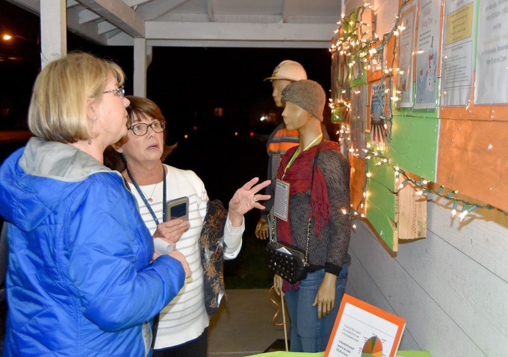 Michele McNany and Karen Birzell talk at the food bank&rsquo;s open house, next to mannequins representing food bank clients.                                Carol Ladwig/Staff Photo