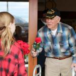 Eva Lindstrand stands outside the Mount Si Senior Center&rsquo;s front doors and gave out roses to the veterans leaving the building. (Evan Pappas/Staff Photo)