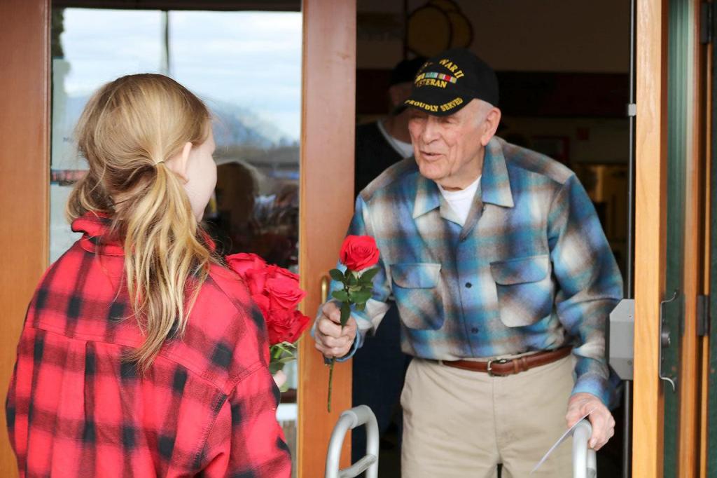 Eva Lindstrand stands outside the Mount Si Senior Center&rsquo;s front doors and gave out roses to the veterans leaving the building. (Evan Pappas/Staff Photo)
