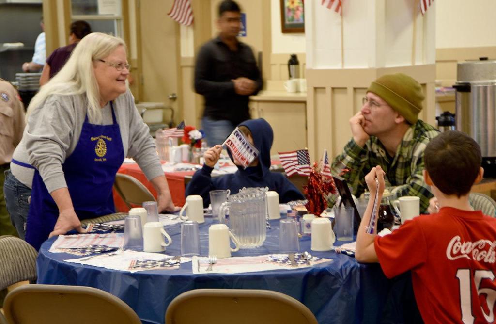 Sandy DuVall, a Rotary volunteer, talks with Calvin, Nate, Janya and Glen Veranth at the breakfast.