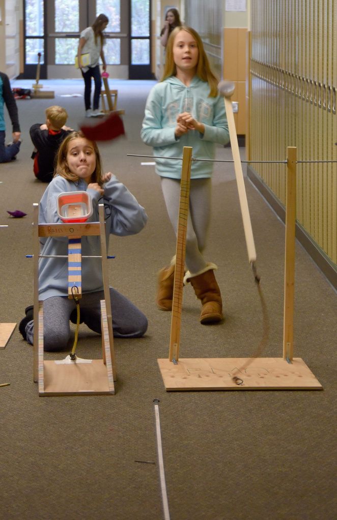 Taya Kappen and Maddi Cole anxiously watch their beanbags fly in a challenge of their two catapults for best distance. Carol Ladwig/Staff Photo