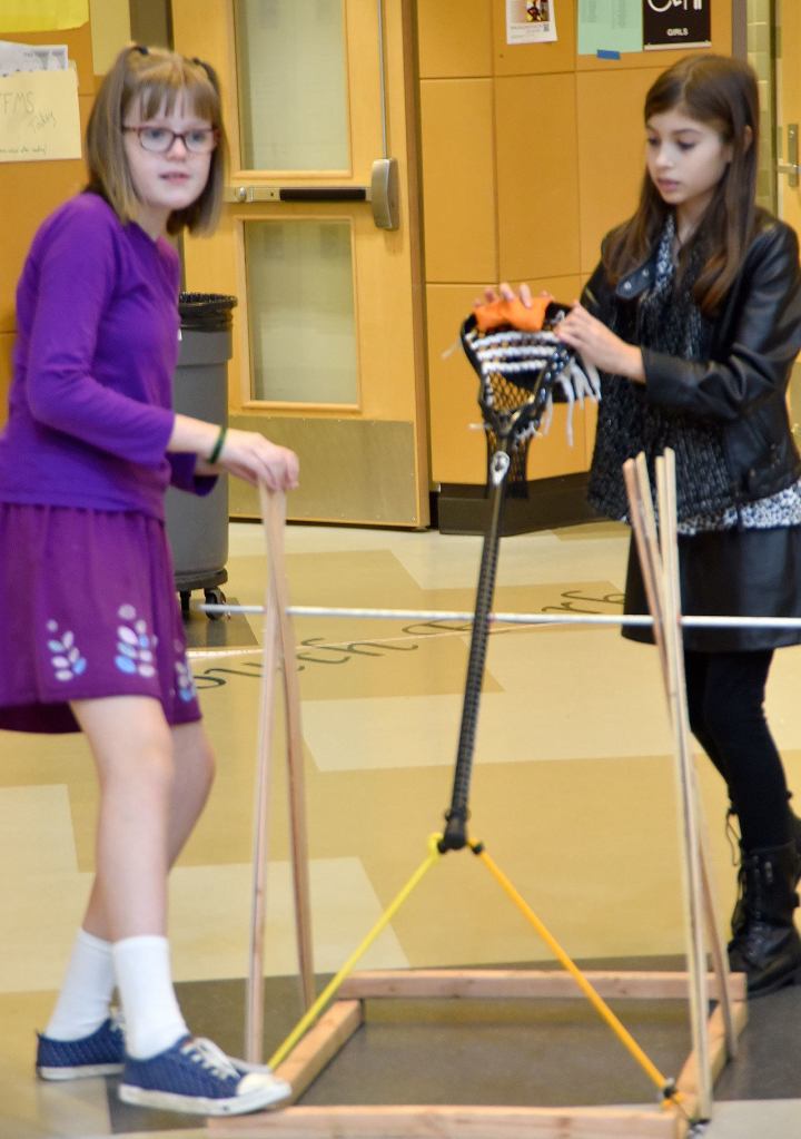 Audrey Hofmann and Evan Symington get ready to launch a beanbag in a hang-time test of their lacrosse-inspired catapult.                                Carol Ladwig/Staff Photo