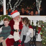 With his tree-lighting duties complete, Santa invites two of his first visitors, Braedon and Adilyn Peterson, to have a seat in the Railway Park gazebo Saturday, while many of his fans watch.