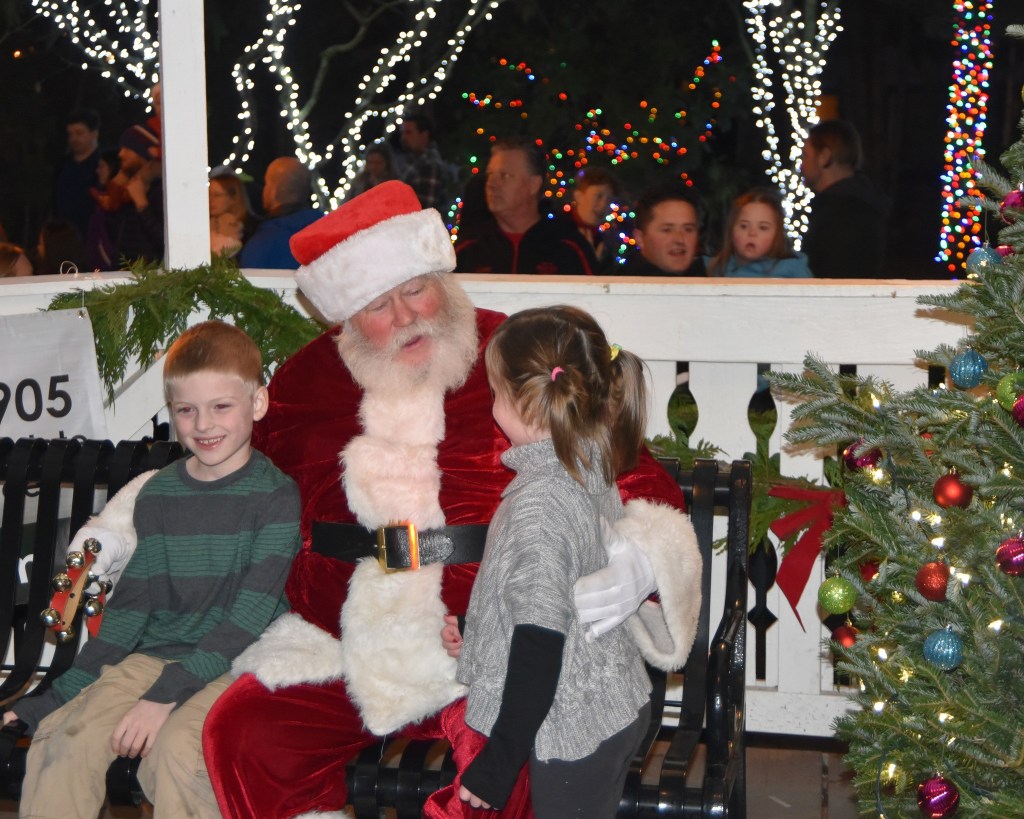 With his tree-lighting duties complete, Santa invites two of his first visitors, Braedon and Adilyn Peterson, to have a seat in the Railway Park gazebo Saturday, while many of his fans watch.