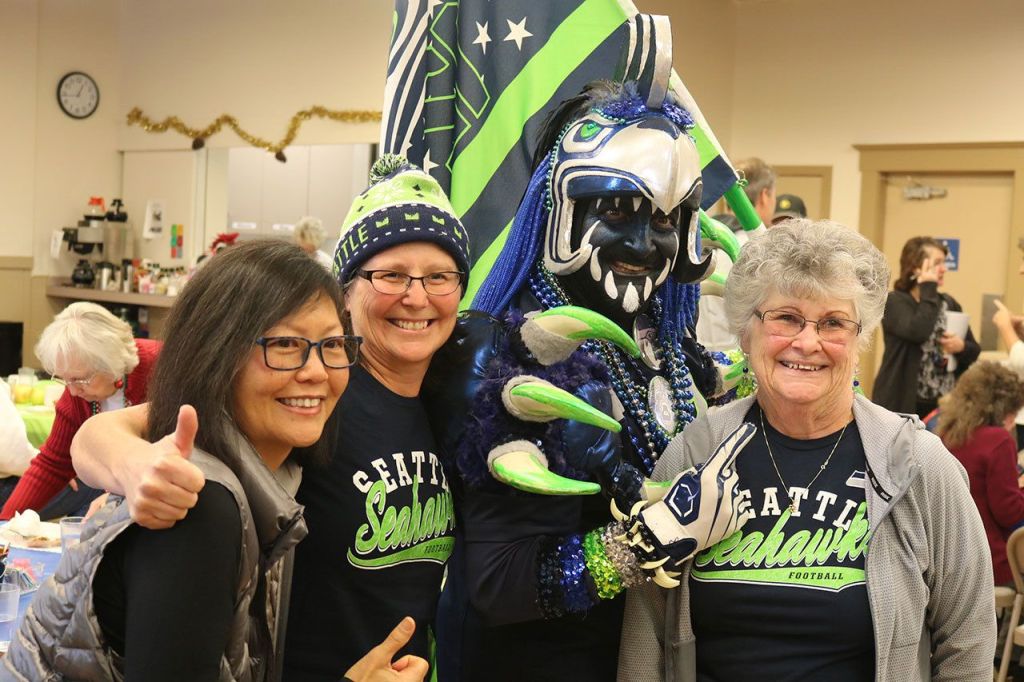 Evan Pappas/Staff Photo                                Jo Takeyama, Janet Kautz and Carol Kautz pose with the Seahawks Rooster, Nick Goins at the Sno-Valley Senior Center 12 Days of Goodness lunch Sept. 21.