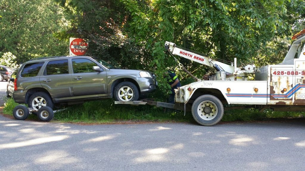 A tow truck hauls off an illegally parked car on Mount Si Road last summer, which became a much more common sight after the DNR got authority from the county sheriff to ticket and tow such trailhead parkers.                                Courtesy Photo