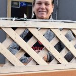 Kimberlea Miller, co-owner of Wildflower Wine Shop, peeks over the lattice surrounding the shop&rsquo;s patio.                                Carol Ladwig/Staff Photo