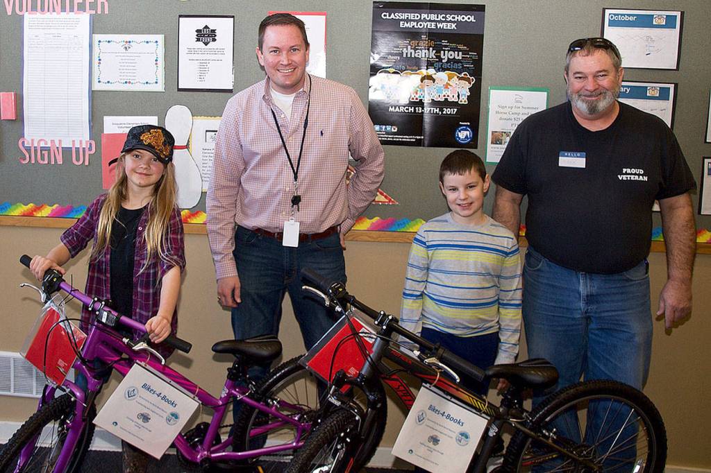 Snoqualmie Elementary School third graders Zoe Hendricks, left, and Carter Cantrell, received bikes and helmets through the North Bend Masons&rsquo; Bikes for Books program, Pictured with the students are SES principal John Norberg, left, and Mark Goodwin, North Bend Masons.                                (Courtesy Photo)