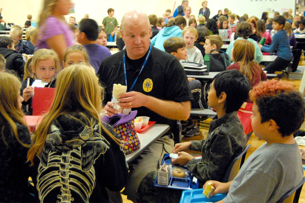During a 2013 visit to North Bend Elementary School, students gather around to have lunch with Chief McCulley. Carol Ladwig/File Photo