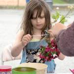 Amirra Edwards, age 8, concentrates on making her flower wreath at the Carnation Farmers Market.                                Carol Ladwig/Staff Photo