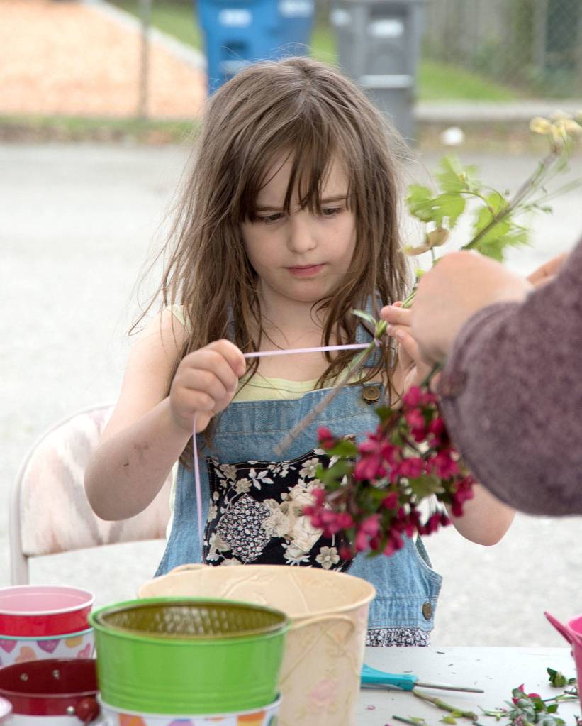 Amirra Edwards, age 8, concentrates on making her flower wreath at the Carnation Farmers Market.                                Carol Ladwig/Staff Photo