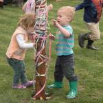 Toddlers Grace Haakenson and Wulfric White, both age 2, examine the Carnation Farmers Market Maypole as their older siblings chase each other around it during opening day festivities, Tuesday, May 2.                                Carol Ladwig/Staff Photo
