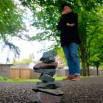 Kirk Mastin stands behind the stack of rocks to create a perspective trick and make the rocks seem taller than they actually are.                                (Evan Pappas/Staff Photo)