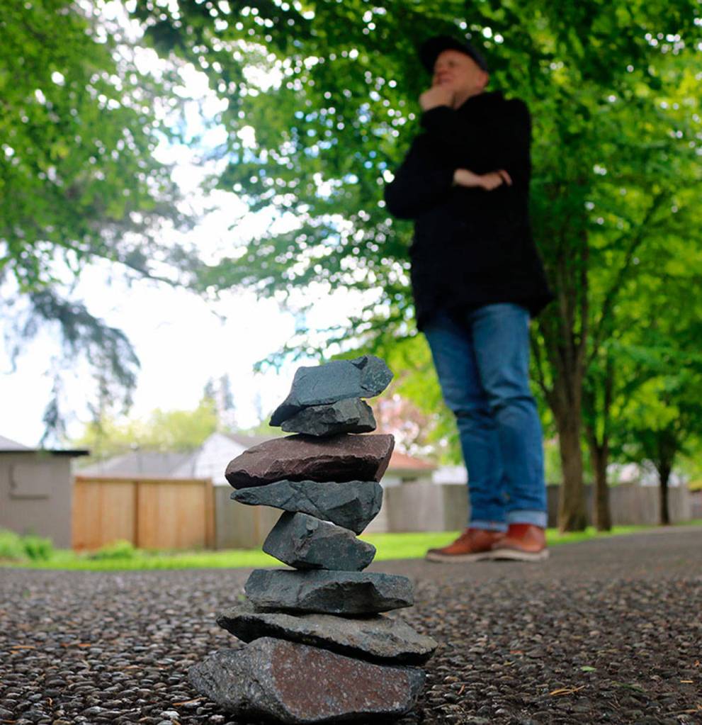 Kirk Mastin stands behind the stack of rocks to create a perspective trick and make the rocks seem taller than they actually are.                                (Evan Pappas/Staff Photo)
